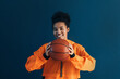 Happy basketball player with a ball over the blue backdrop. Smiling woman with a basketball looking at the camera in studio.