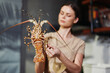 Woman holding lobster in kitchen for seafood cooking inspiration and culinary preparation concept