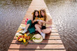 Two happy women by the lake eating food on the dock