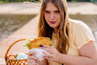 Woman happily enjoying a bagel with lettuce and cheese outdoors in nature