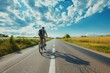 Bicyclist on empty open road under blue sky