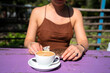 A girl with a cup of cappuccino with coconut milk and a chocolate raw food, vegetarian cake.