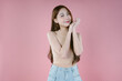 Portriat of Beautiful young Asian woman in sleeveless sweater standing, warm winter cold season fashion accessories trend, posing and looking at camera on pink studio background isolated.