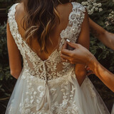Fototapeta  - Mujer cerrando el vestido de una novia por detrás