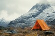 Orange tent with mountains on the background in cloudy day