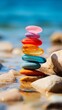 A stack of colorful rocks on a beach. The rocks are arranged in a pyramid shape. The colors of the rocks are red, orange