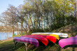 Canoe club station concept: set of colorful canoes lay near lake shore
