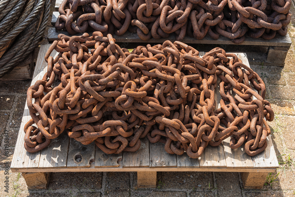 metal rusty chains lie outside on top of wooden industrial pallets