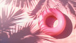 Pink inflatable ring with the shadow of some palm trees. - copy space