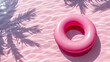 Pink inflatable ring with the shadow of some palm trees. - copy space