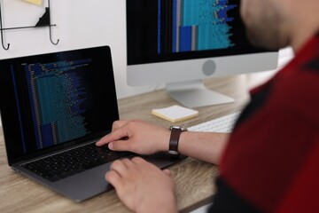 Programmer working with laptop at desk in office, closeup