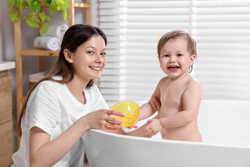 Wall Mural - Mother bathing her cute little baby in tub at home