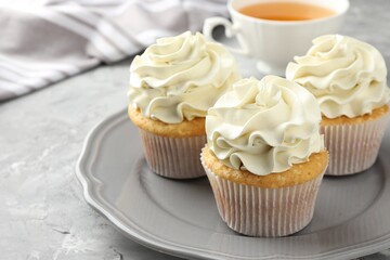 Tasty cupcakes with vanilla cream on grey table, closeup