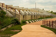 A pathway ascends towards a concrete flood control structure adorned with multiple barriers and metal railings, meticulously designed to serve as a flood control barrier. 