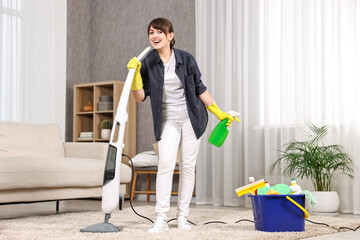 Poster - Happy young housewife with spray bottle having fun while cleaning carpet at home