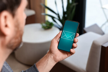 Canvas Print - Man received message on mobile phone indoors, closeup. Envelope illustration on device screen