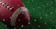 A close-up of football resting on green turf with confetti around