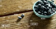 Blueberries are spilling from teal bowl onto a wooden surface