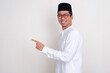 © KrishnaTedjo - Moslem Asian man smiling at the camera with one hand pointing beside him