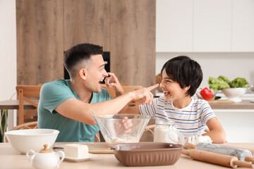 Canvas Print - Little boy with his father having fun while cooking in kitchen