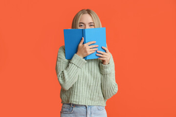 Wall Mural - Beautiful young woman with book on red background