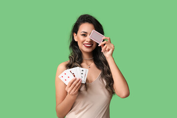 Wall Mural - Beautiful young African-American woman with playing cards on green background