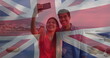 Image of flag of uk flag over happy diverse couple taking selfie by sea