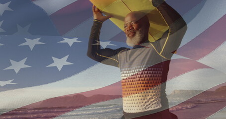 Wall Mural - Image of flag of usa over happy senior african american man with surfboard on beach