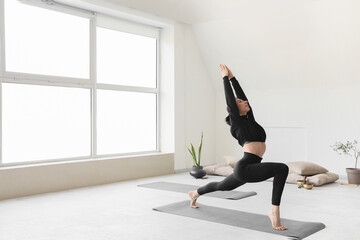Wall Mural - Sporty young woman practicing yoga on mat in gym