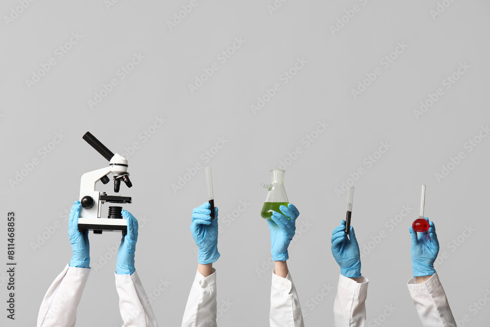 Scientist's hands holding microscope, test tubes with soil, green and red liquids on white background