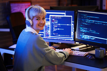 Canvas Print - Female programmer with headphones working in office at night