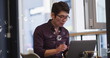 Asian male in his middle age, wearing glasses, focusing on laptop