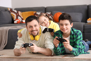 Poster - Happy father with his little children playing video game on floor at home