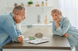 © Pixel-Shot - Sad mature couple counting money at table in kitchen