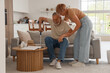 © Pixel-Shot - Mature woman helping her husband with crutch to stand up from sofa at home