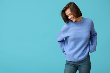 Poster - Beautiful young woman in stylish sweater on blue background