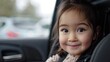A young girl is sitting in a car seat and smiling