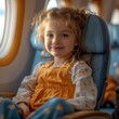 A young girl is sitting in a blue and yellow airplane seat, smiling