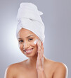© peopleimages.com - Portrait, woman and towel for cream or cosmetics, moisturizer and hand on white background. Skincare, dermatology and beauty for female person, smile or relax for lotion with glow and product on face
