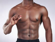 Studio, bodybuilder and person with pill, muscle and supplement healthy for body of athlete. Wellness, strong and man with abs, chemical and medication for treatment in white background or remedy