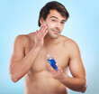 Skincare, portrait and bottle product in studio with natural cosmetics for dermatology routine in morning for clear soft skin. Person, blue background and aftershave for grooming, hygiene and fresh.