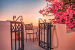 Summer sunset vacation scenic of luxury famous Europe destination. White architecture in Santorini, Greece. Stunning travel honeymoon with pink flowers chairs, terrace sunny blue sky. Romantic tourism