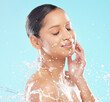 Woman, studio or splash for skincare or wellness in shower, cosmetic or cleaning and hydration, Female person, blue background or dermatology with water and makeup, healthy skin or facial in bathroom