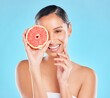 Model, beauty and grapefruit with skincare glow from spa treatment and natural cosmetics. Woman, skin and face of person relax after dermatology detox in a studio with blue background feeling healthy