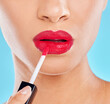 Woman, mouth and red lipstick in studio, application and cosmetics makeup on blue background. Female person, beauty and confident lips for glossy grooming, skin care and makeover transformation