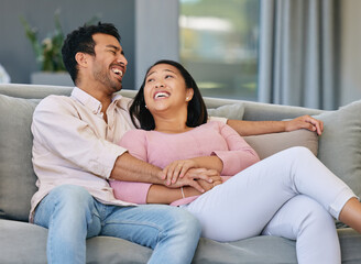 Wall Mural - Asian couple, happiness and relax on sofa in living room for love, support or conversation. Laughing, weekend and married man with funny woman in lounge for joke, comedy or bonding together in home