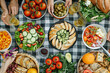 Summertime Picnic Spread. Aerial view of a colorful outdoor picnic with fresh veggies, bread, and olives.