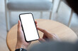 © tippapatt - Mockup, using cell phone in a cafe coffee shop. Woman holding using smartphone with blank screen for display your graphic ads, mobile app. close-up