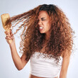 Beauty, brushing hair or curly and angry woman in studio on gray background with moody expression. Anger. hair and salon with African model looking annoyed at aesthetic or cosmetology routine