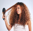 Anger, beauty or curly and woman brushing hair in studio on gray background with moody expression. Angry. hair and salon with African model looking annoyed at aesthetic or cosmetology routine